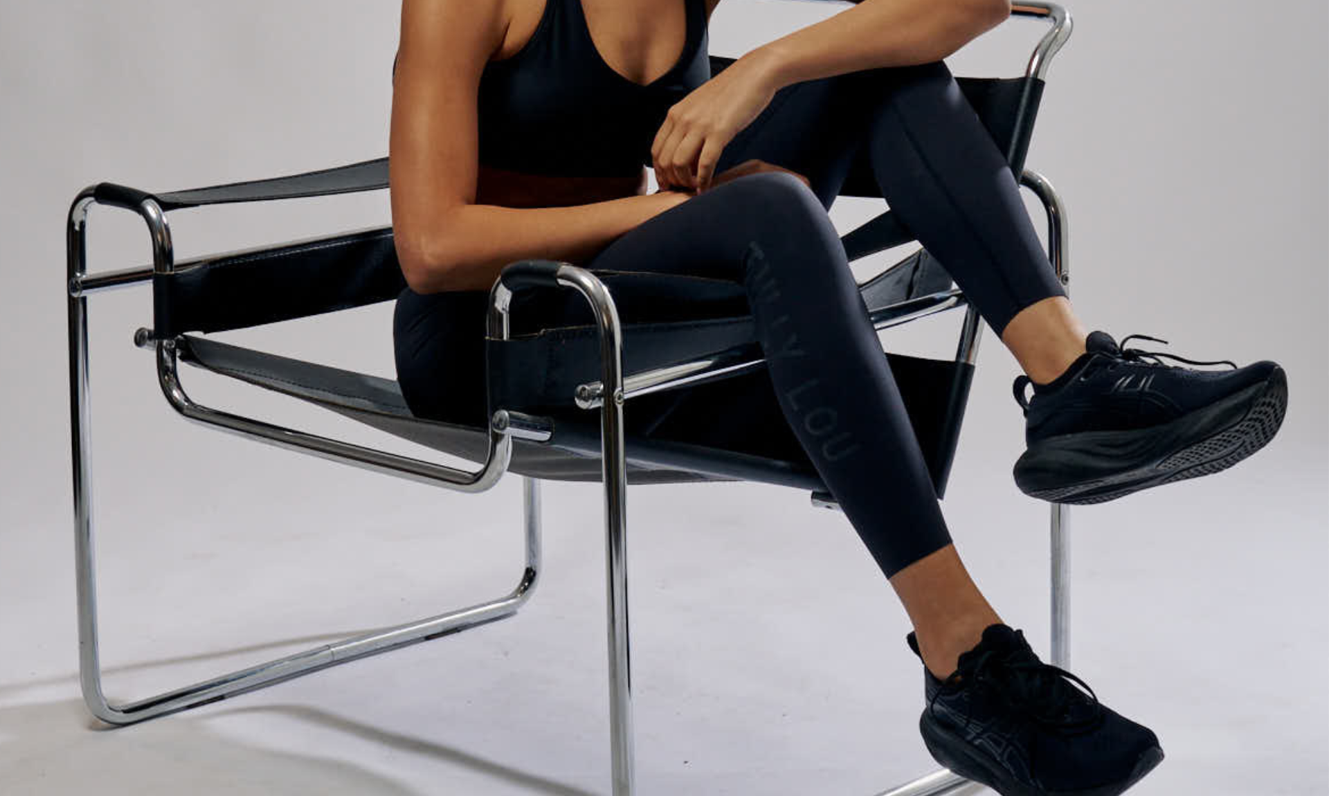 Person wearing black athletic wear sitting on a modern chair.
