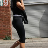 Woman in black athletic wear walking outdoors with a building and number 49 in the background.