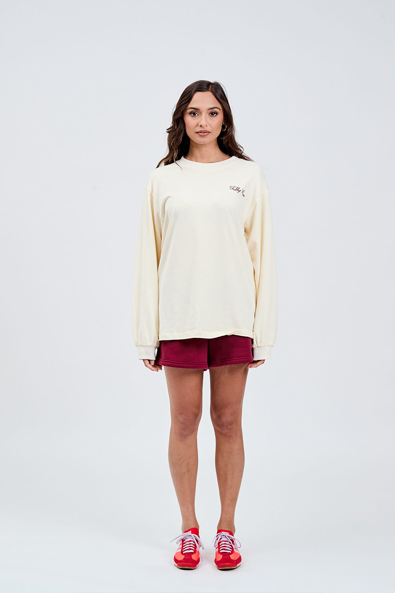 front view of butter yellow long sleeve top with burgundy italic embroidery Tully Lou left side of chest with burgundy shorts