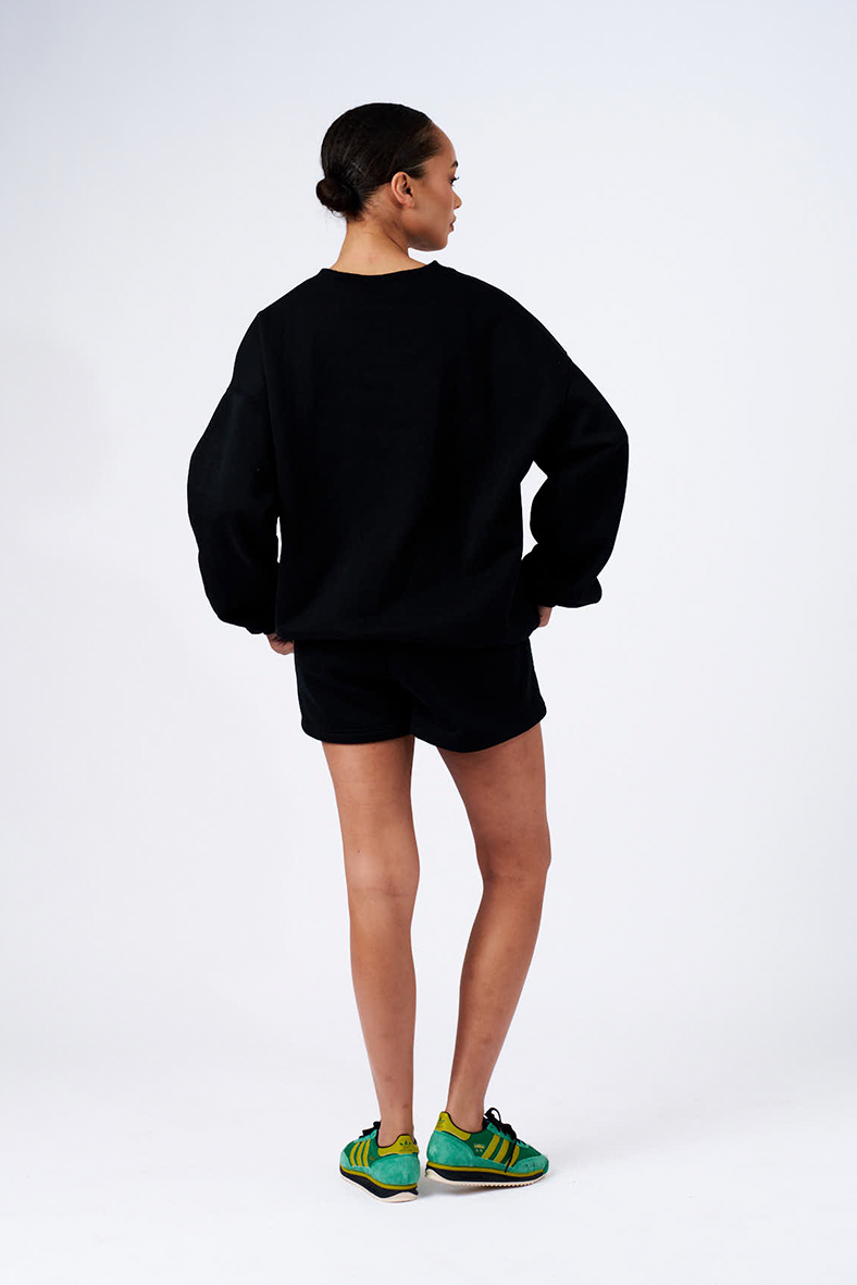 back image of model wearing black milano crew neck boyfriend sweater with matching lounge shorts 