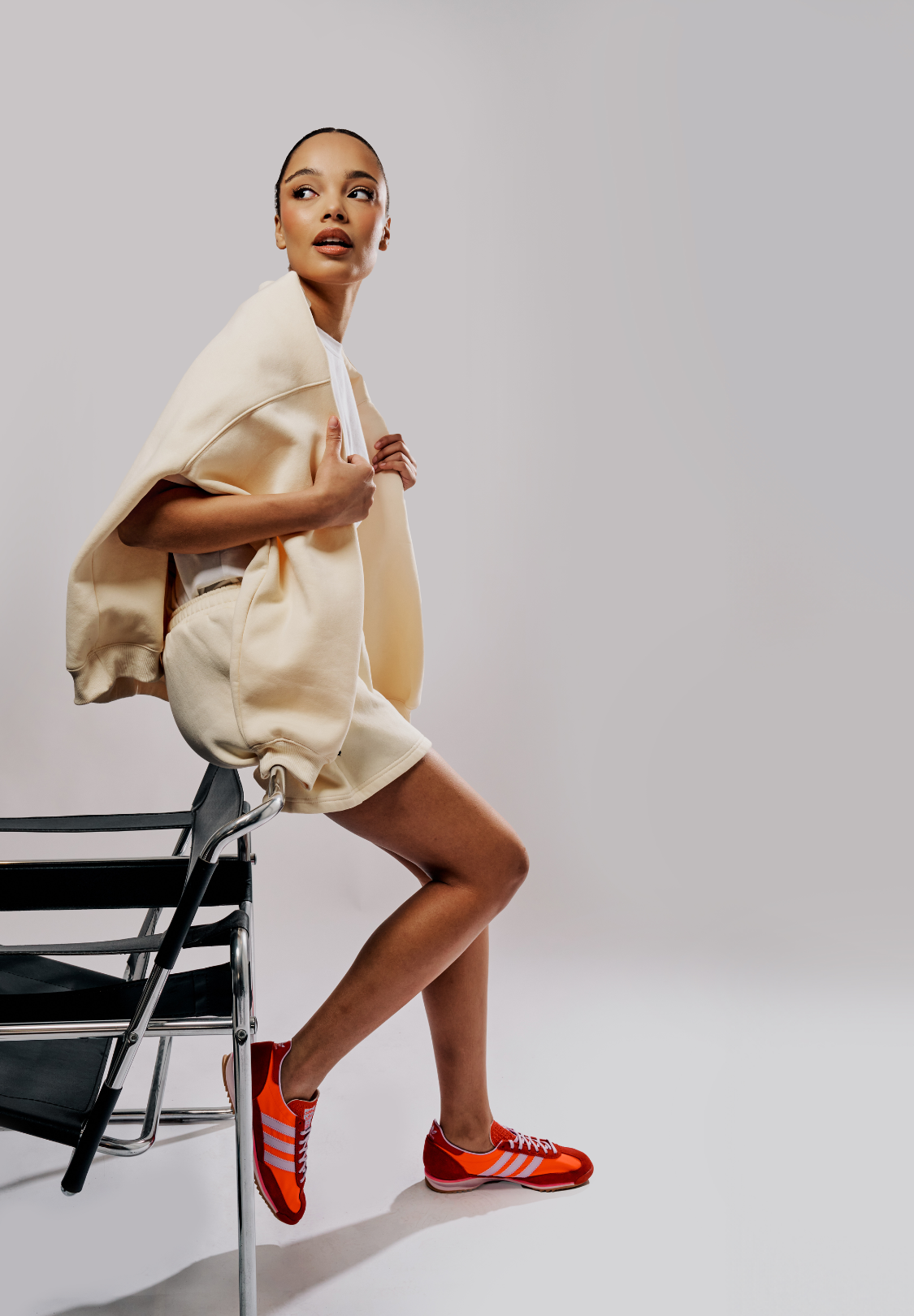 model leaning on a chair with butter yellow matching shorts and crew neck jumper cropped for mobile