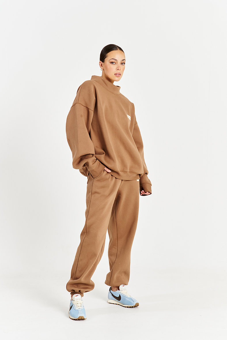 model wearing matching mocha brown track pants and brown jumper with high neck
