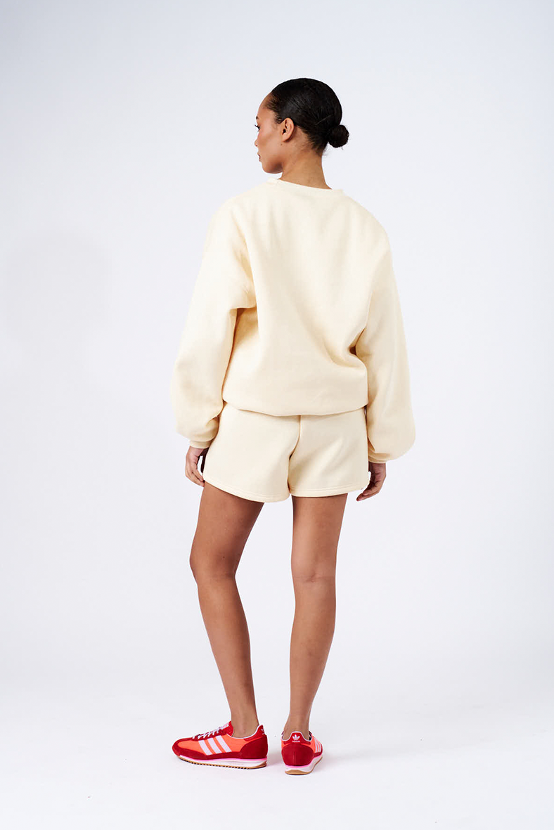 back view of model wearing butter yellow shorts and oversized boyfriend sweater 