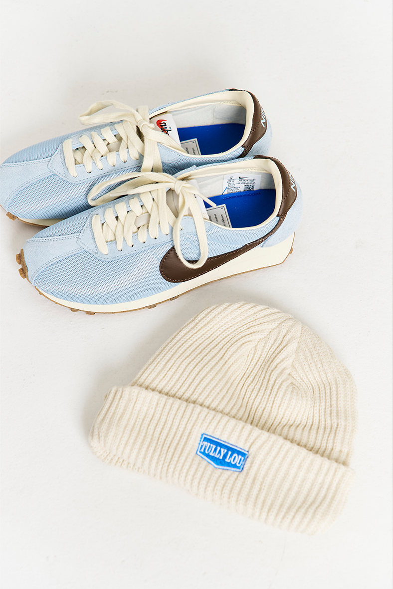 white beanie flat lay image styled next to nike light blue and brown sneakers 