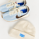 white beanie flat lay image styled next to nike light blue and brown sneakers 