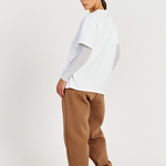 back of white tee layered with long sleeve top and brown track pants 