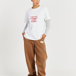 model wearing white tee with red text logo and brown track pants 