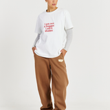 model wearing white tee with red text logo and brown track pants 