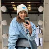 white beanie with blue logo on model posing in a mirror