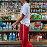 Person standing in a store aisle with shelves stocked with various products